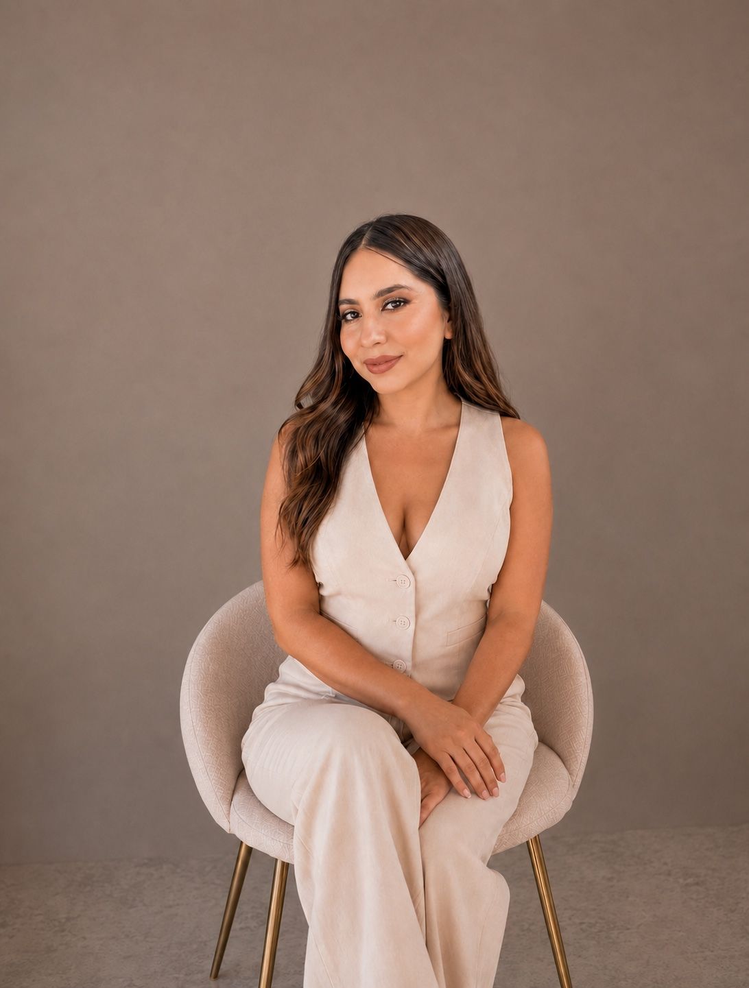 Michelle Corona sentada en una silla, vestida en tonos marfil
