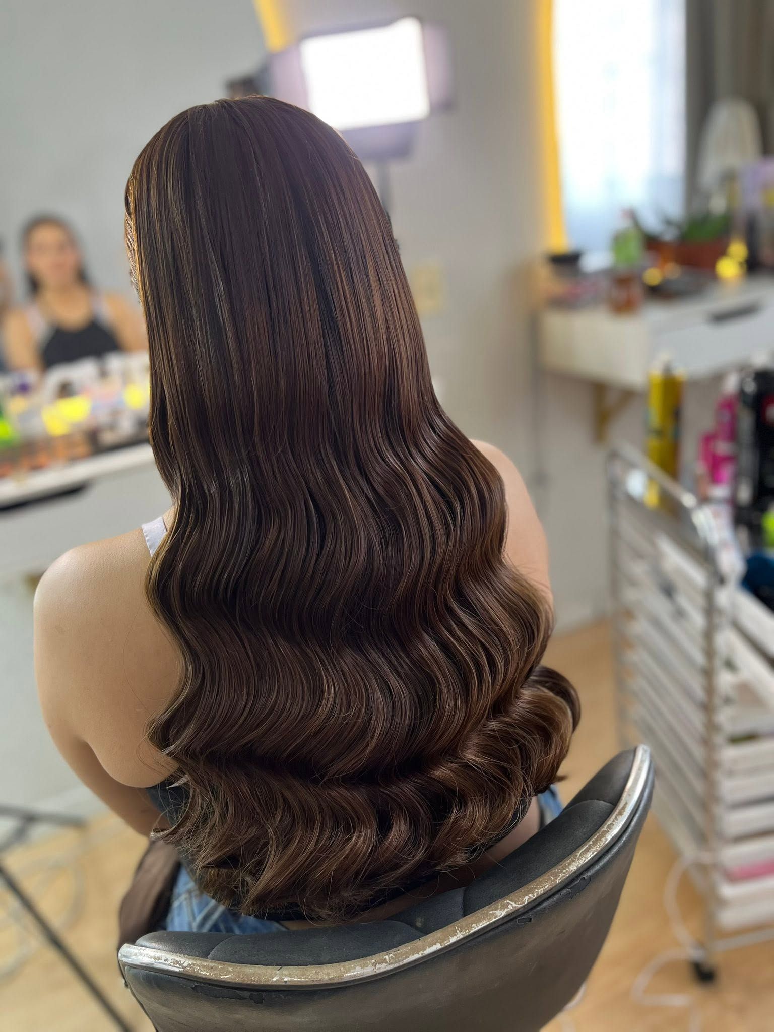 Vista posterior de un peinado largo con ondas pulidas en cabello castaño