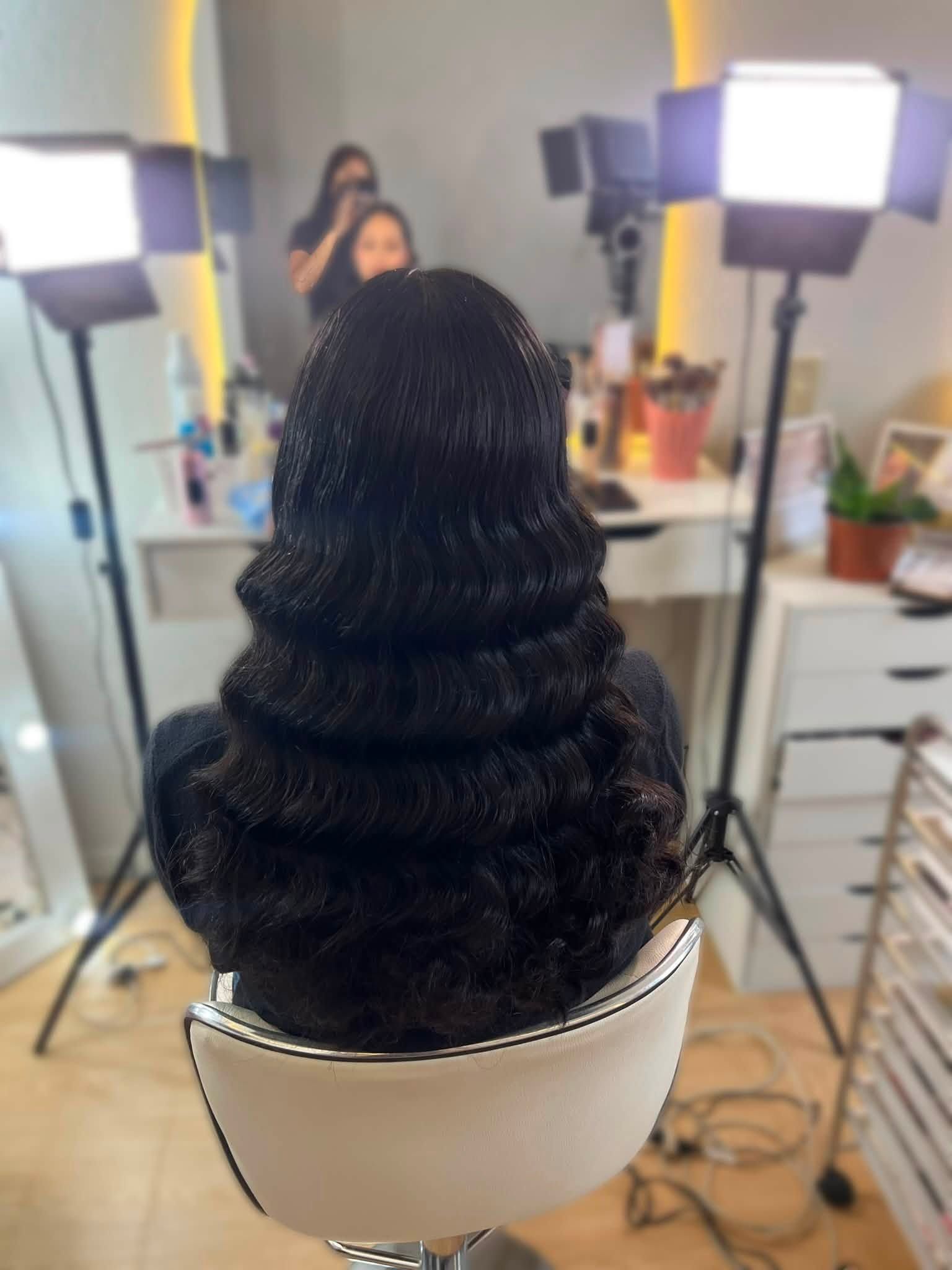 Ondas uniformes en cabello negro largo frente a un espejo del estudio