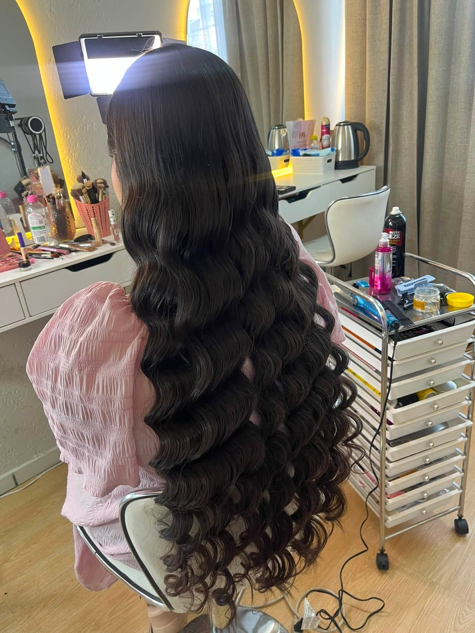 Cabello largo oscuro con ondas definidas y una cinta rosa, visto desde atrás
