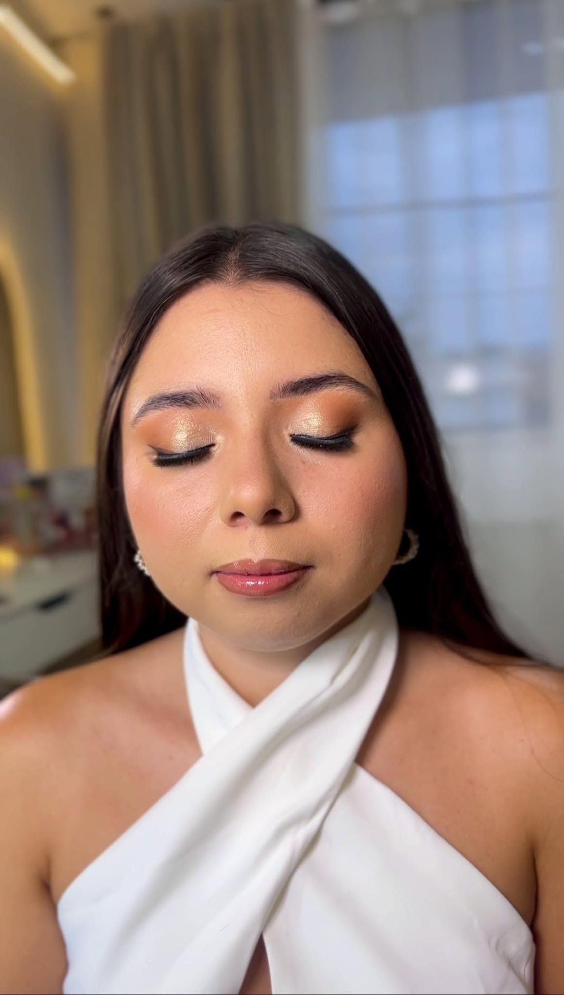 Maquillaje social dorado con labios nude y blusa blanca cruzada